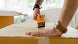 Una persona chiude con il nastro adesivo una scatola da trasloco